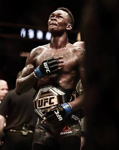 Adesanya clutches the interim belt, hand on heart
